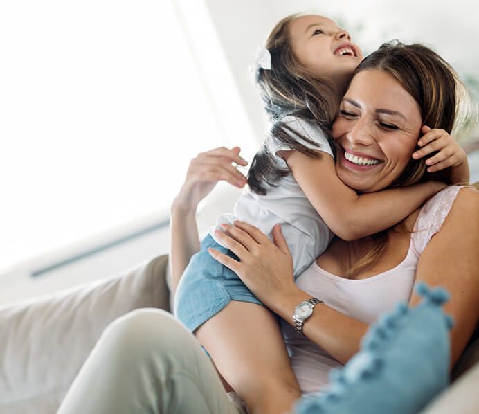 mother smiling with daughter as they embrace